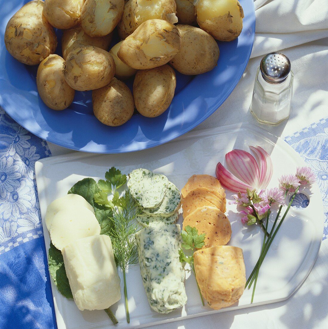 Rolls of seasoned butter & plate of potatoes cooked in skins