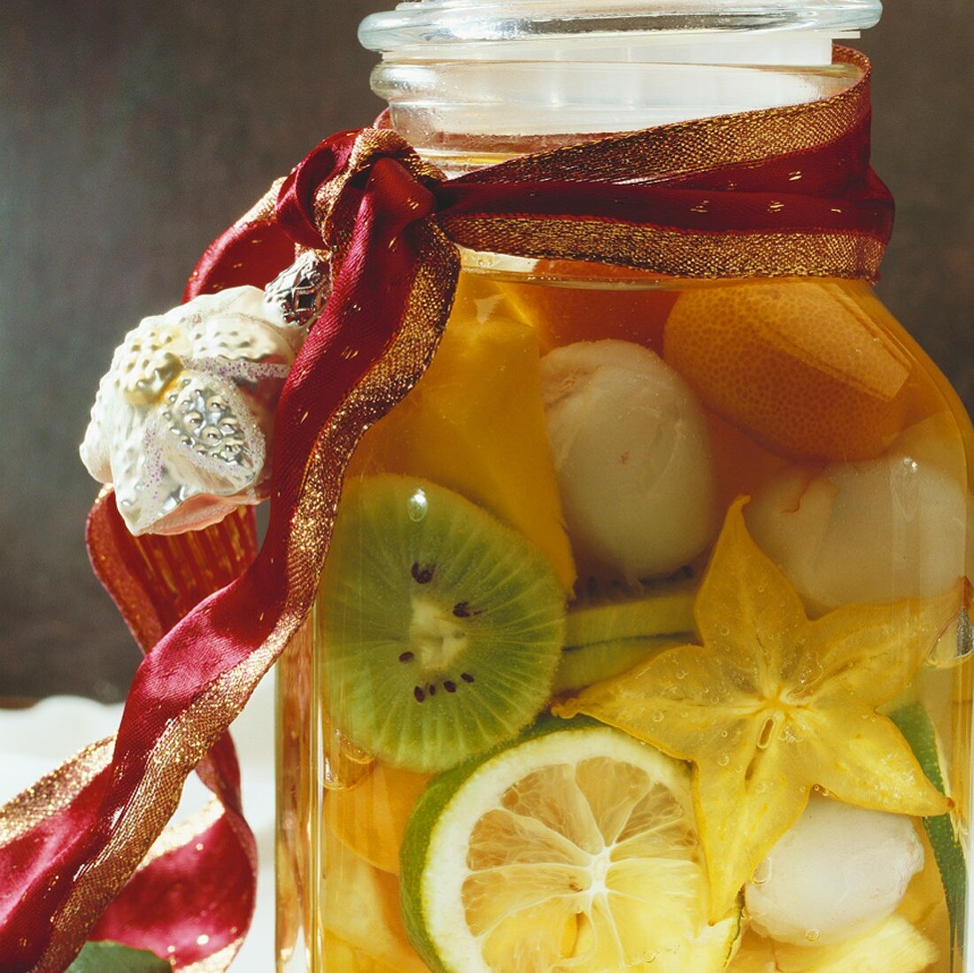 Rumtopf with exotic fruit in glass jar with gift ribbon