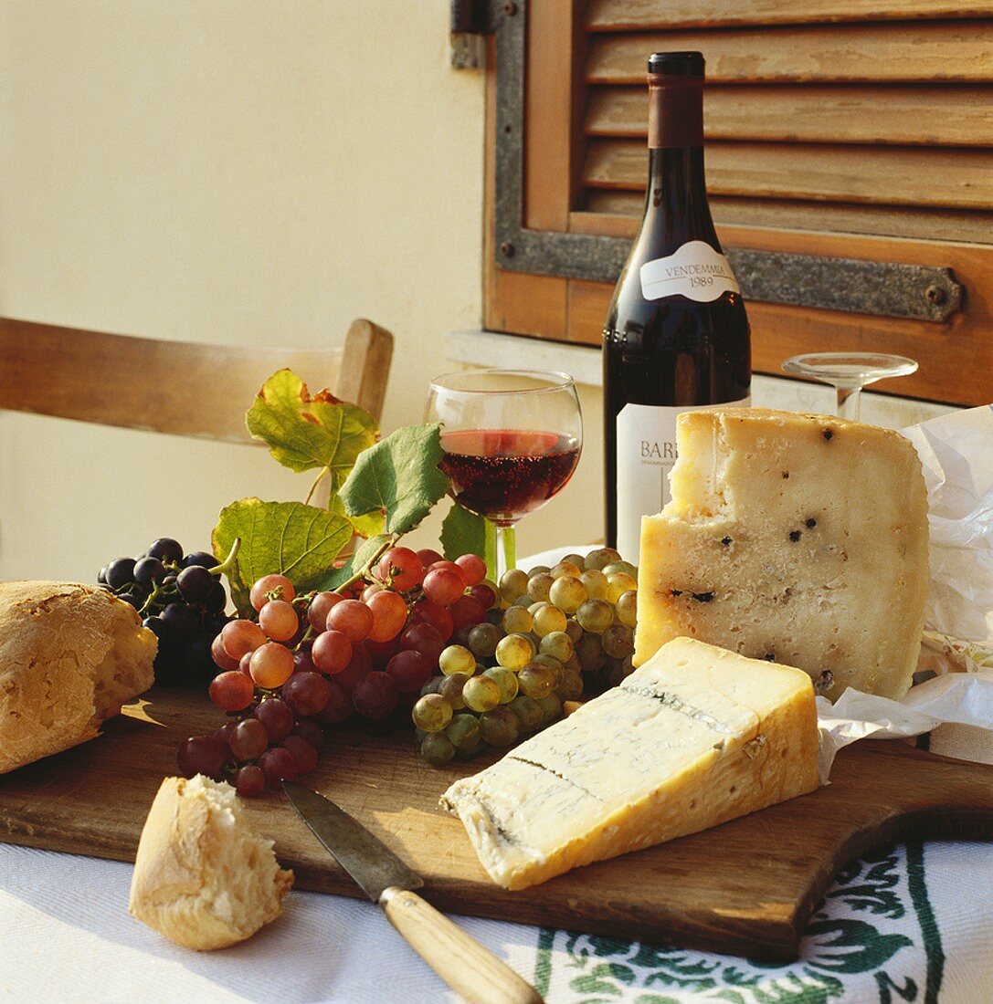 Still life with cheese, bread, wine and grapes