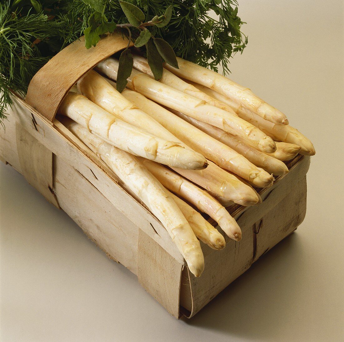 White asparagus and fresh herbs in woodchip basket