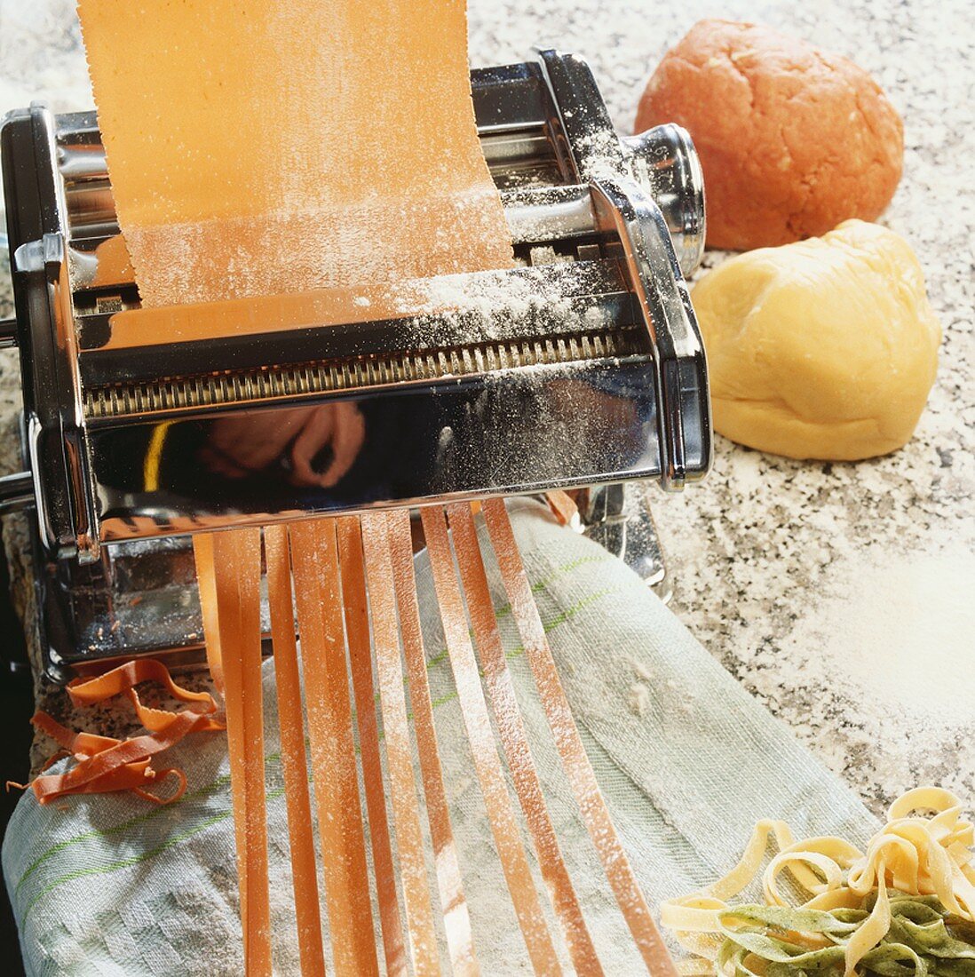 Red pasta dough passing through a pasta maker