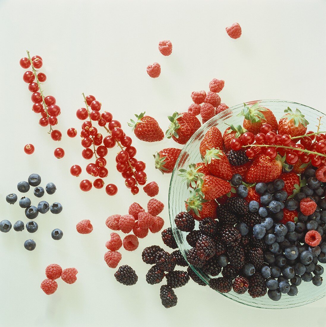 Fresh berries in and beside a glass bowl
