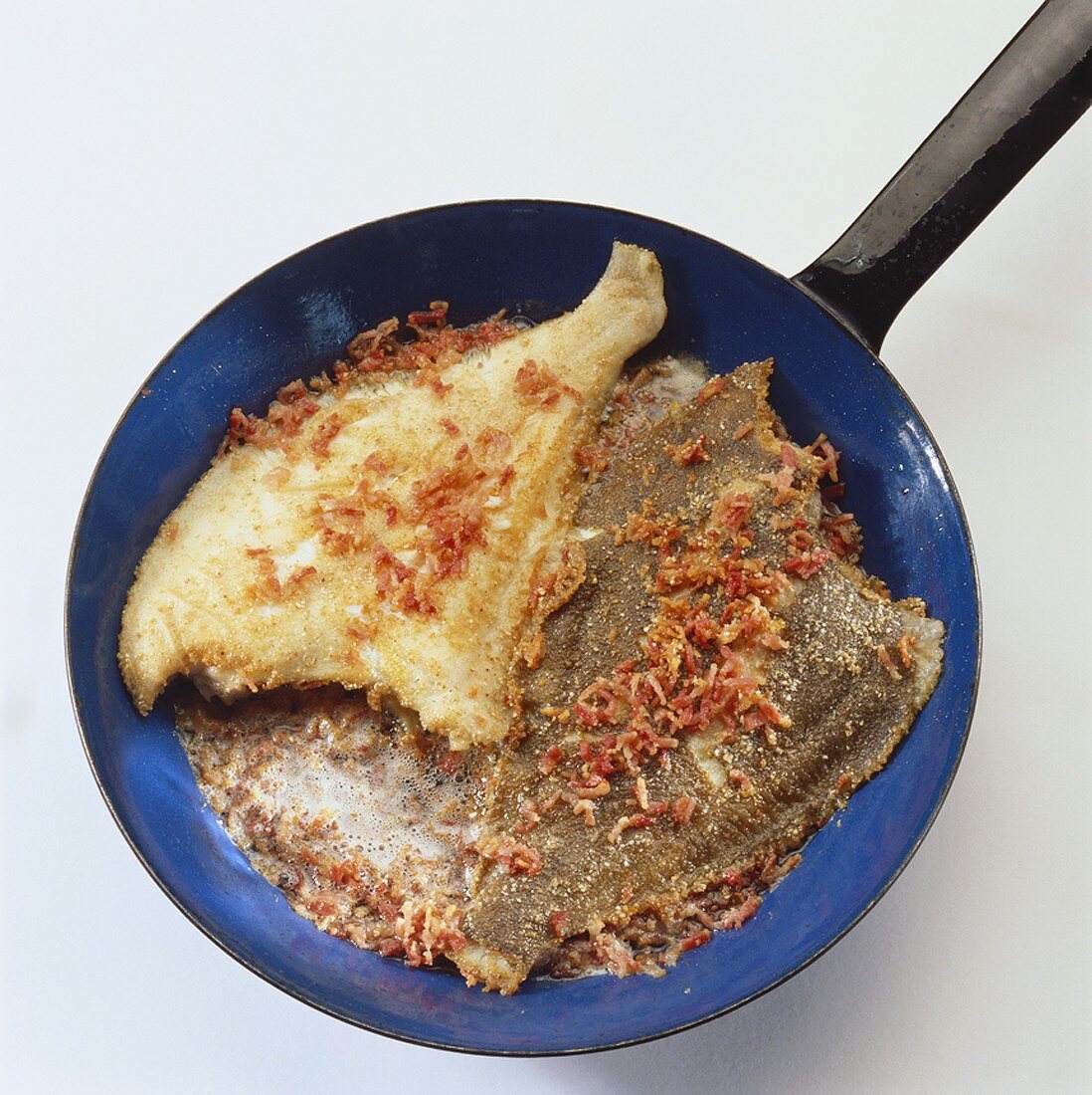 Plaice with bacon in a frying pan