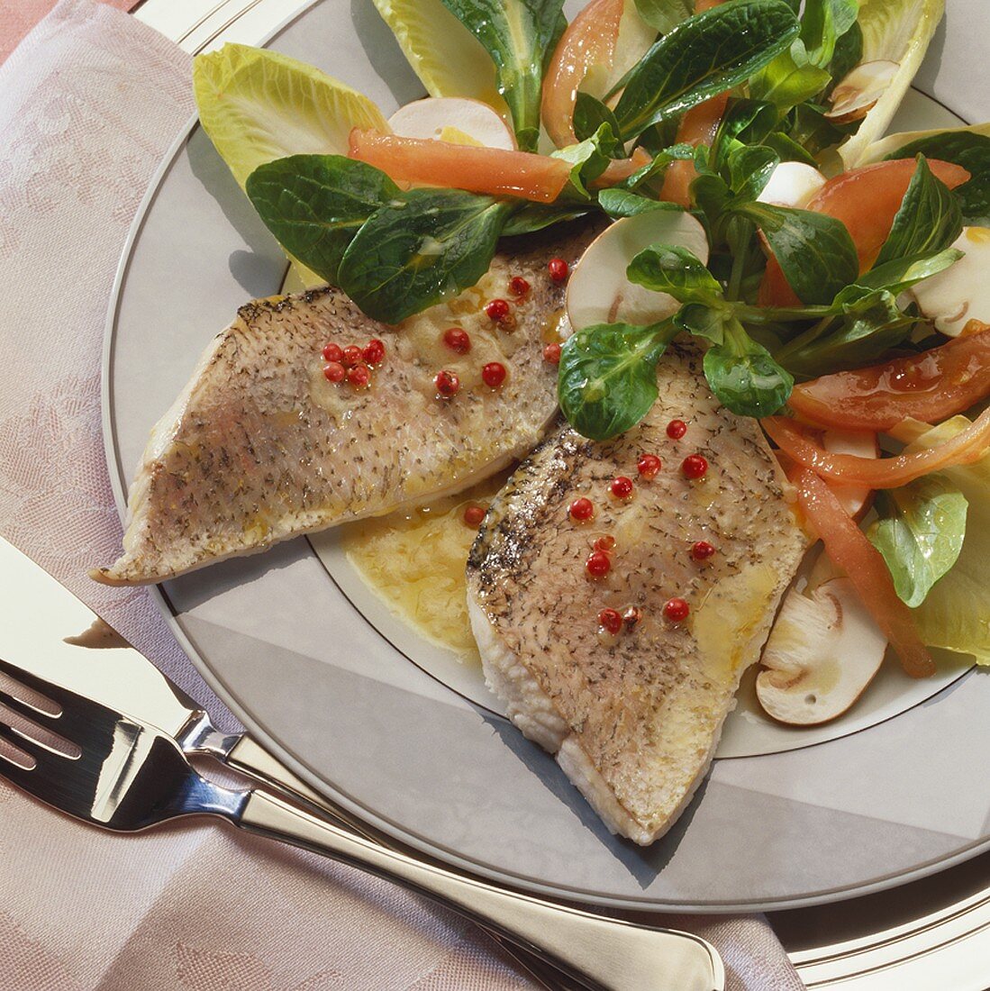 Fillet of pike with red peppercorns on salad