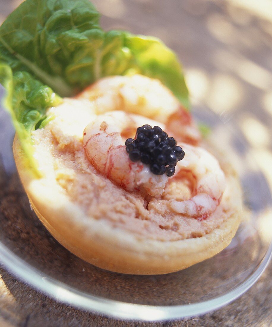 Half a bread roll topped with prawns and caviar