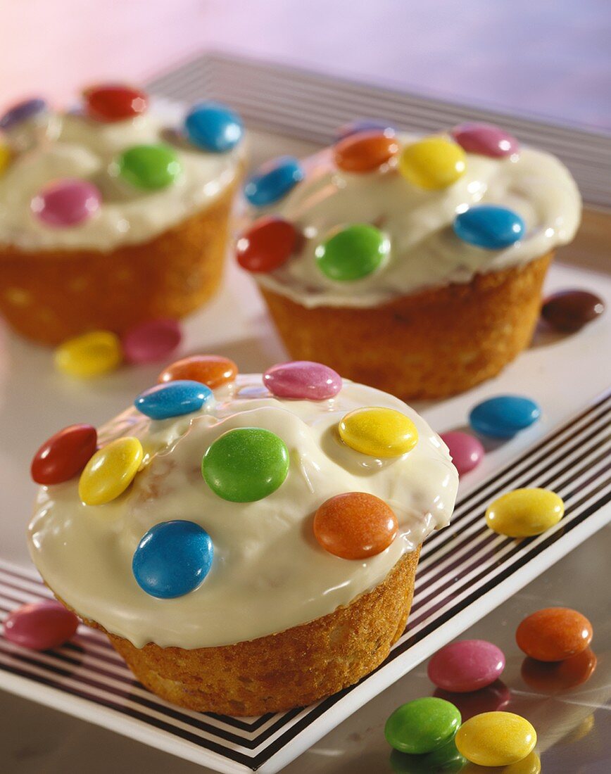 Muffins with white chocolate icing & coloured chocolate beans