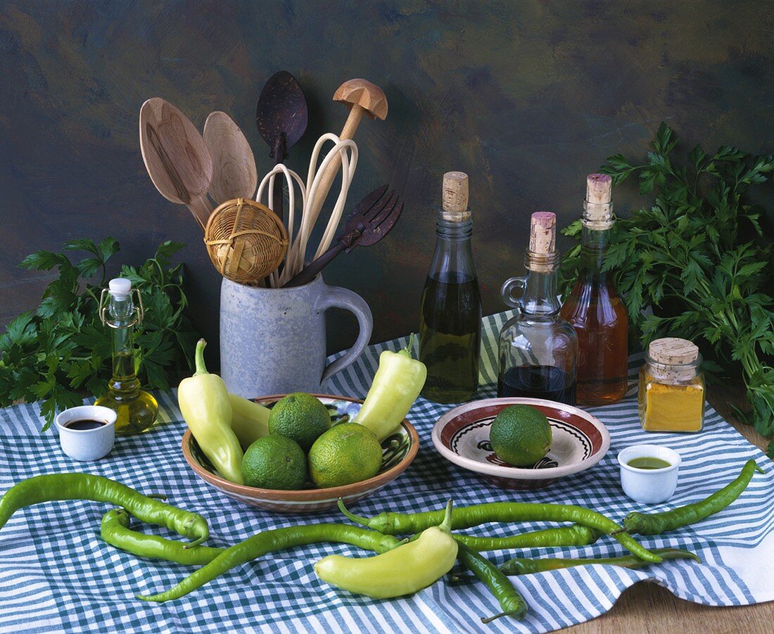 Tisch mit Spitzpaprika, Peperoni, Limetten, Essig und Öl