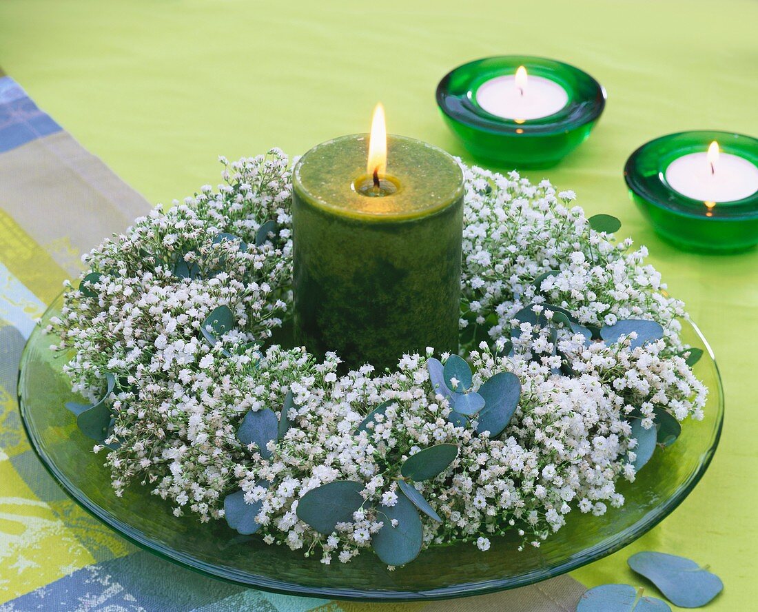 Wreath of gypsophila and eucalyptus around green candle