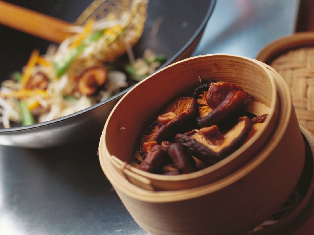 Steamed shiitake in bamboo basket, stir-fried vegetables behind