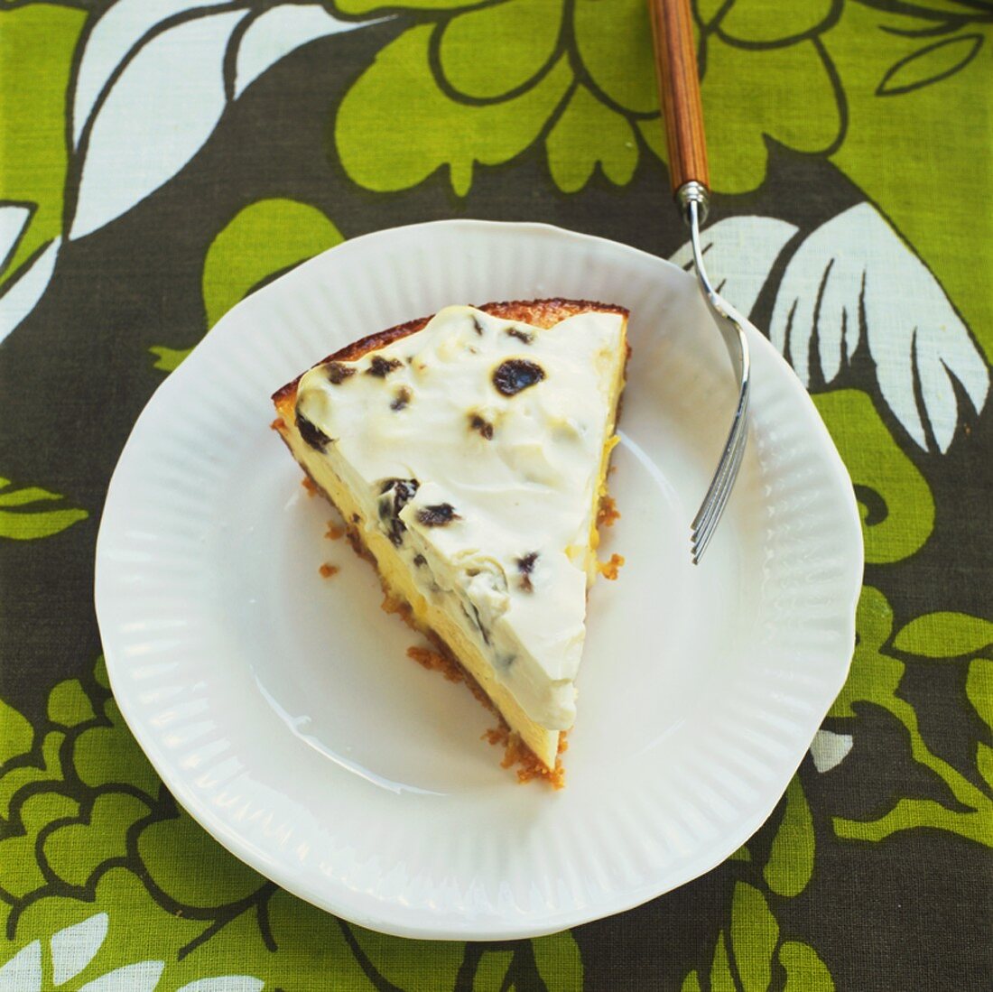 A piece of cheesecake with raisin cream topping