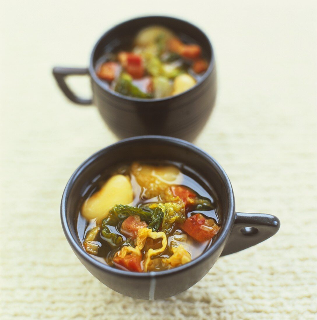 Kohl-Bohnen-Suppe in zwei schwarzen Tassen