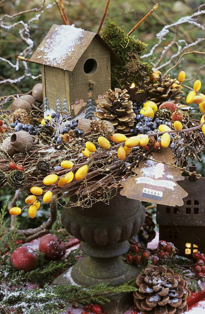 Ein Vogelhäuschen in einem winterlichen Gesteck