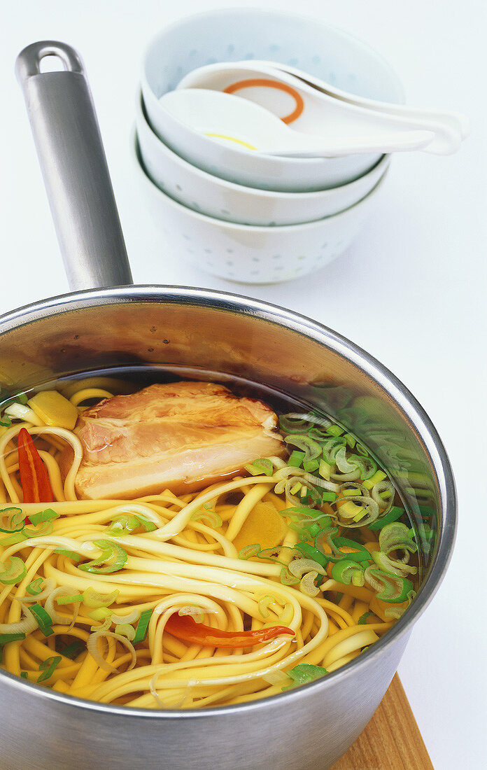 Asian noodle soup with bacon and spring onions