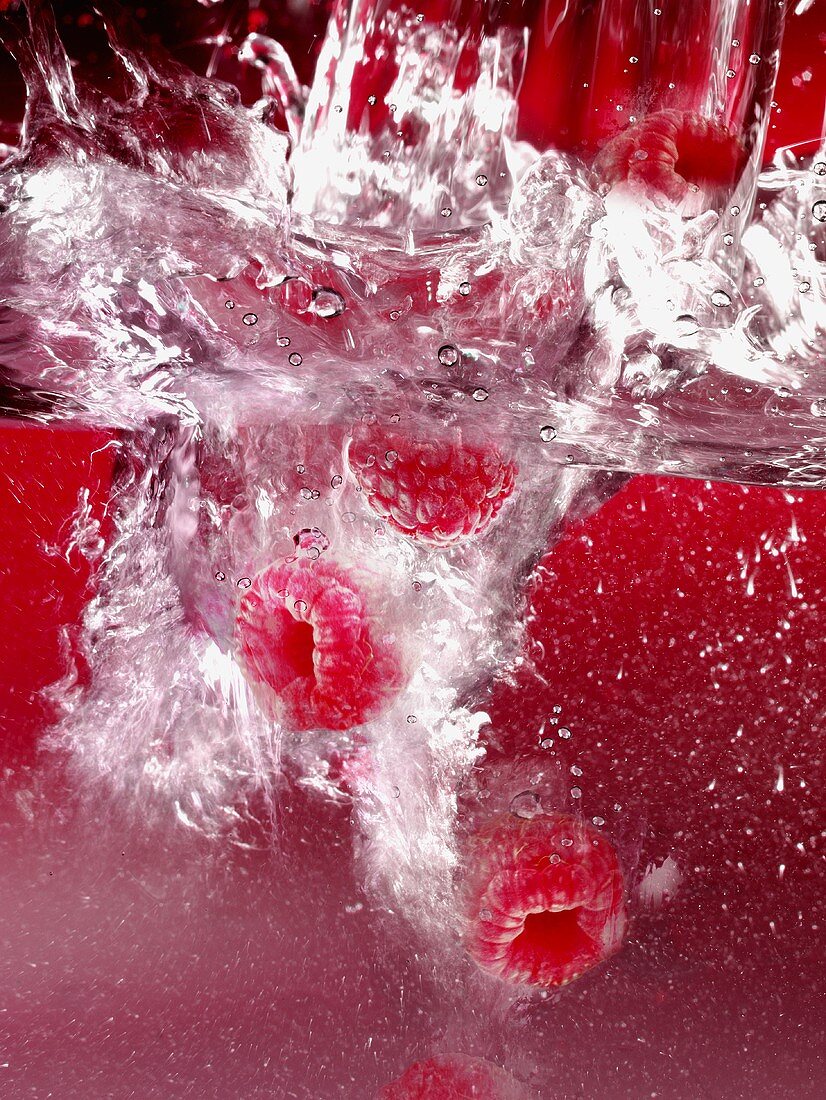 Raspberries falling into water