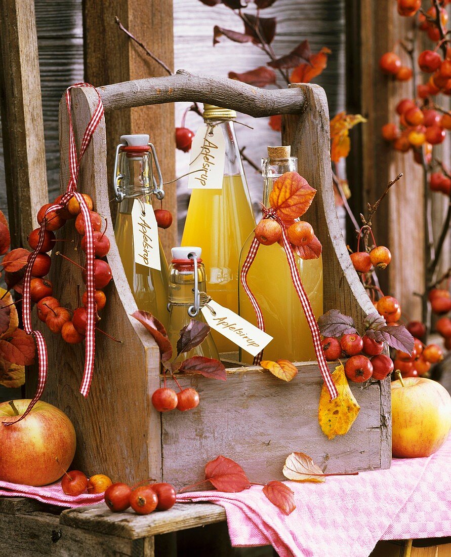 Four bottles of home-made cloudy apple juice in wooden carrier