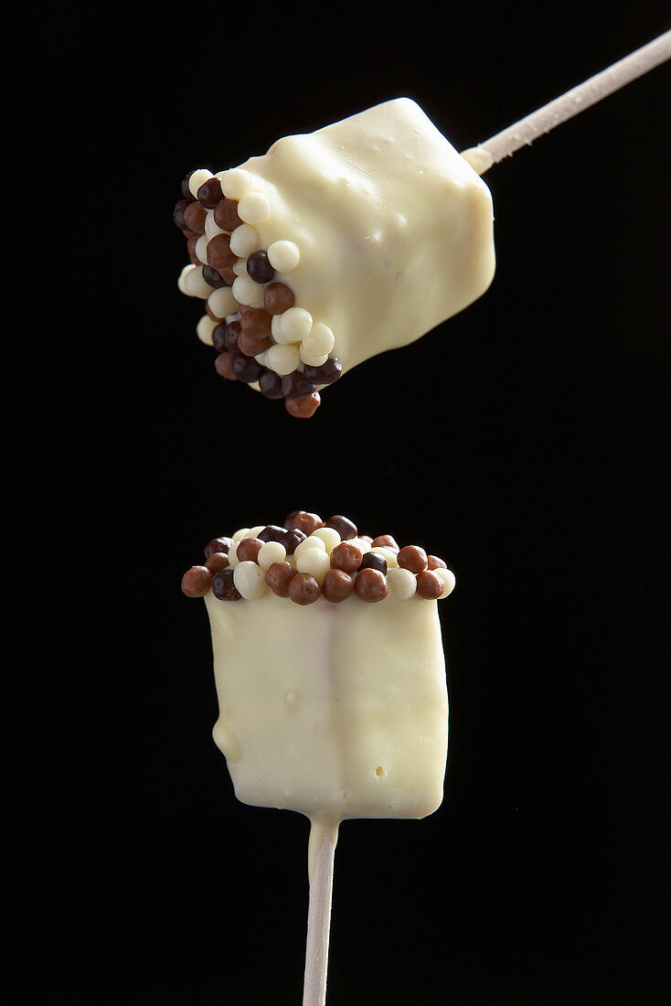 Two white chocolate lollipops with tiny chocolate balls