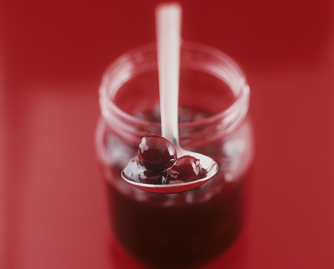 Cherry jam in jar and on spoon