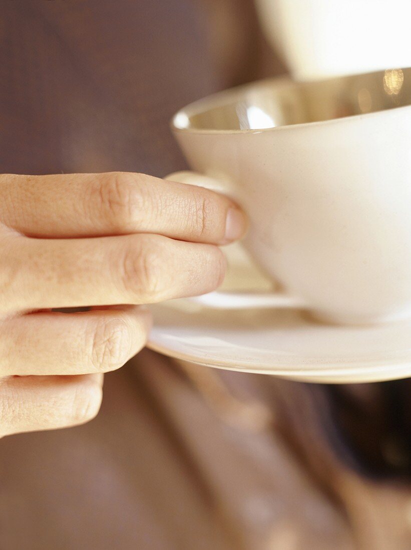 Hand hält Kaffeetasse