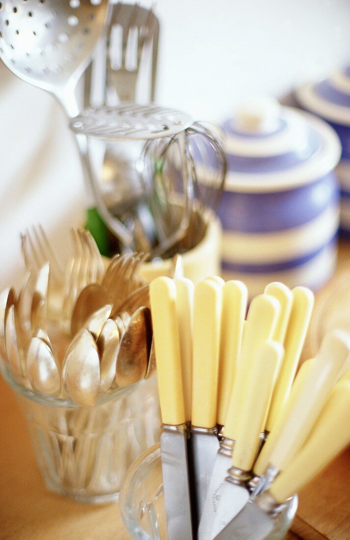 Cutlery in glasses and crockery in background