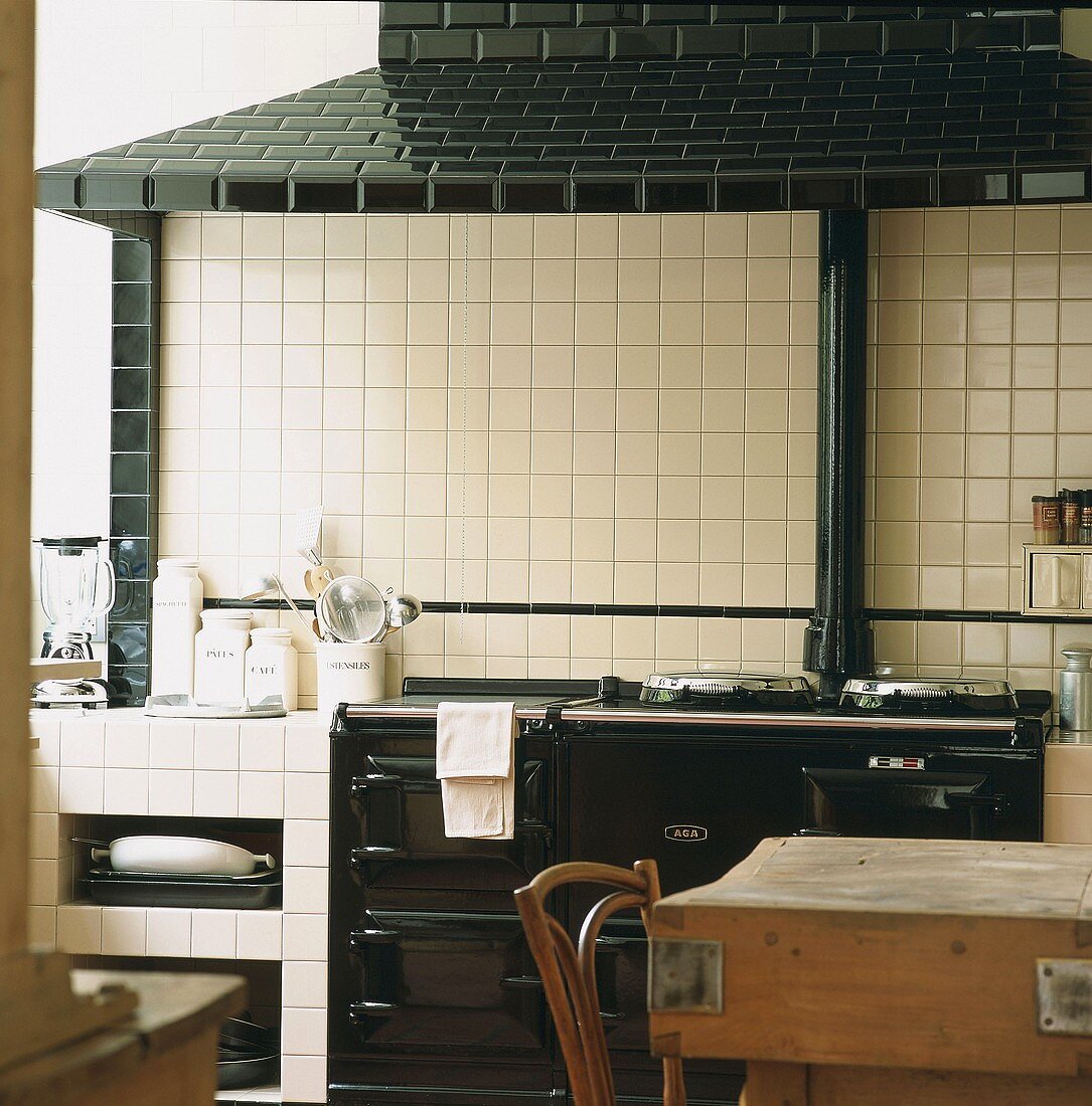 White tiled kitchen with antique black cooker and black tiled extractor hood