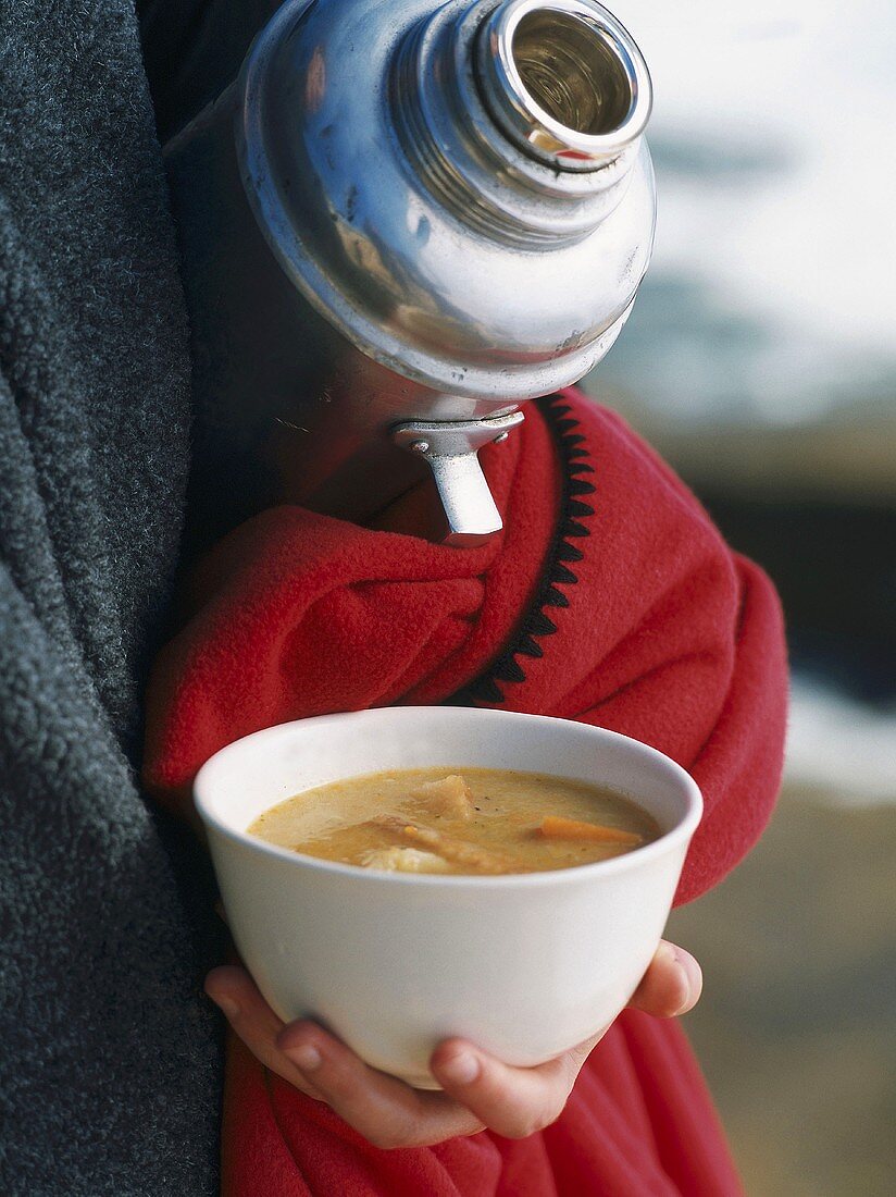 A hand holding a bowl of soup