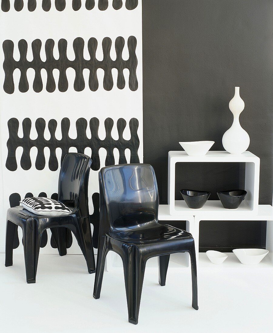 Black plastic chairs in front of black and white wallpaper