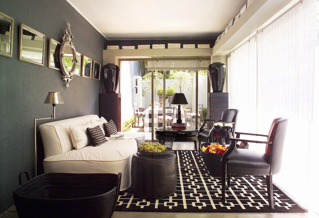 Schwarz-weißes Zimmer mit Couch und Ledersessel vor Fensterfront