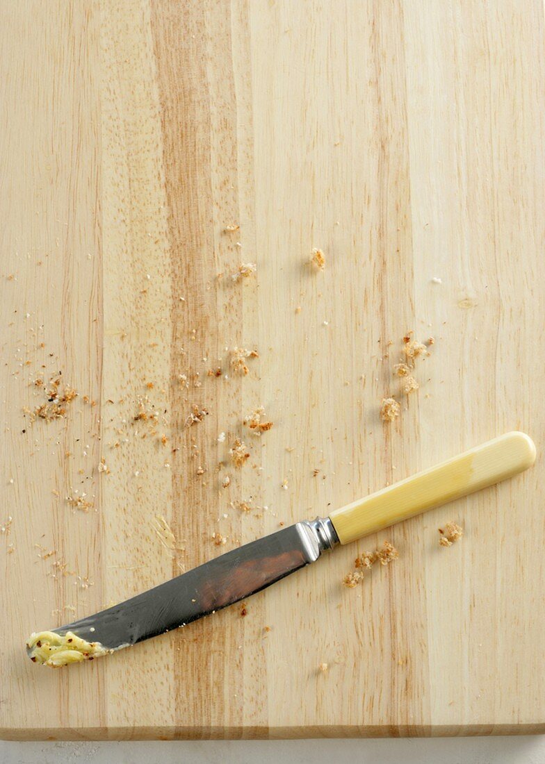 Brotkrümel und Messer auf Brett