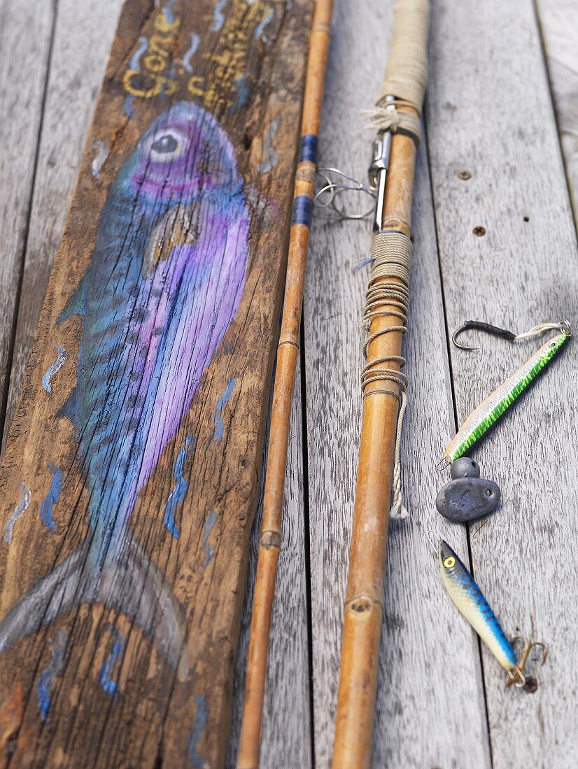 Stillleben mit Angelzubehör und auf Holz gemaltem Fisch