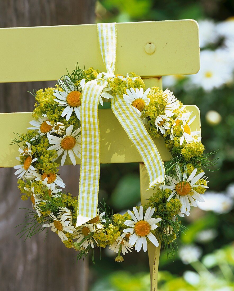 Wreath of spring flowers on chair back in garden