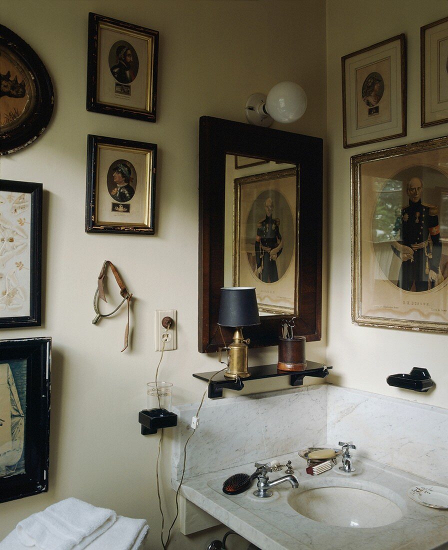 Collection of antique pictures above marble sink in corner of bathroom