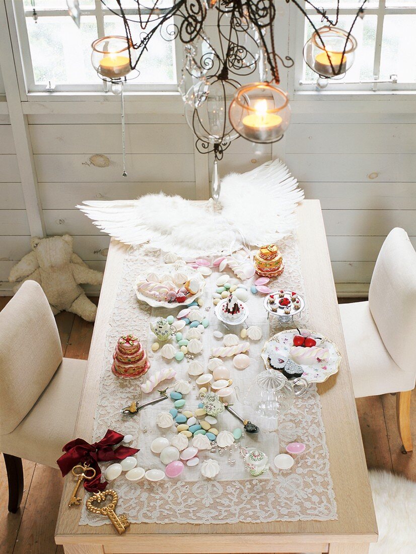 A view of a table laid for Christmas decorated with angel wings, Christmas biscuits and cake and festive decorations