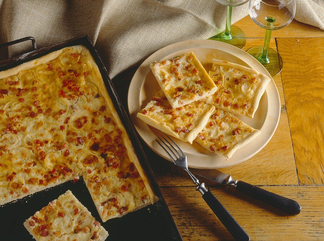 Flammkuchen auf Backblech und Teller