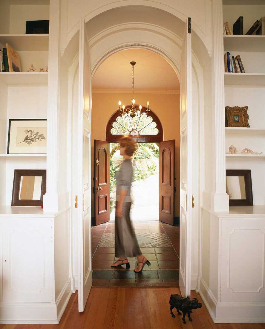 View through open living room doors into corridor with front door at far end