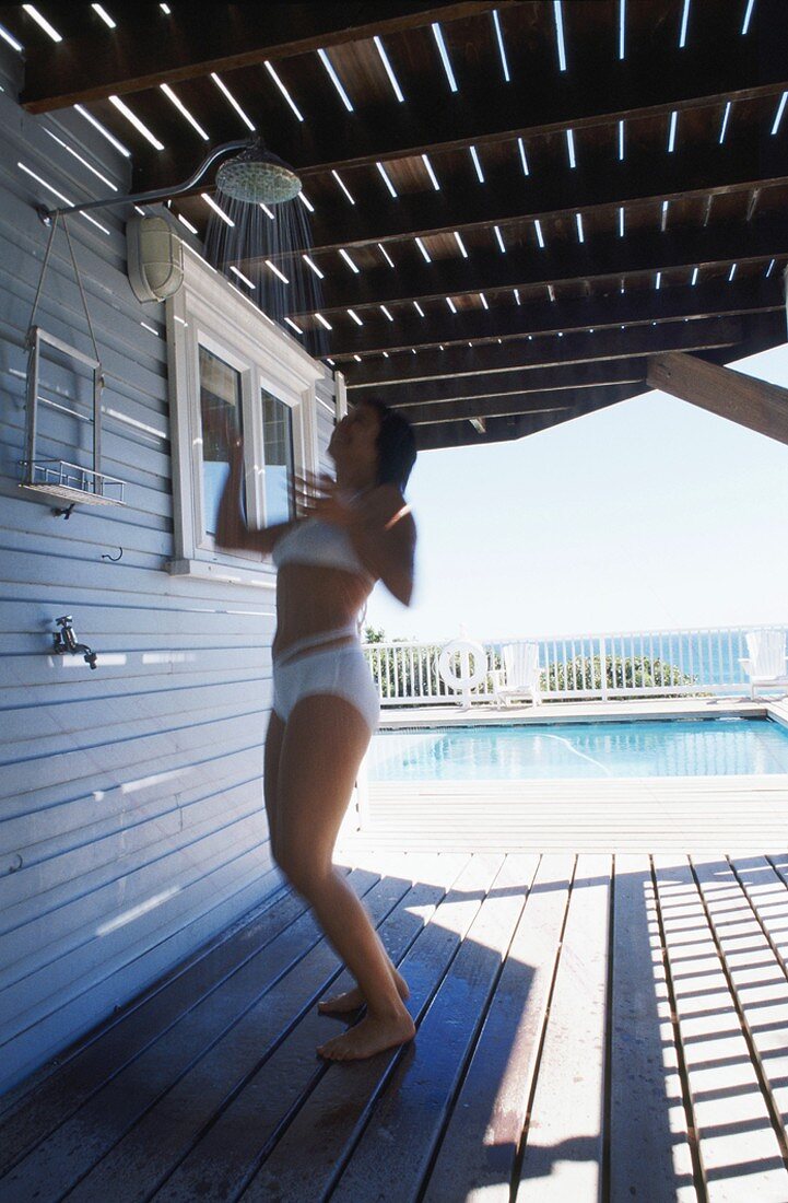 Frau duscht auf Veranda neben Schwimmingpool