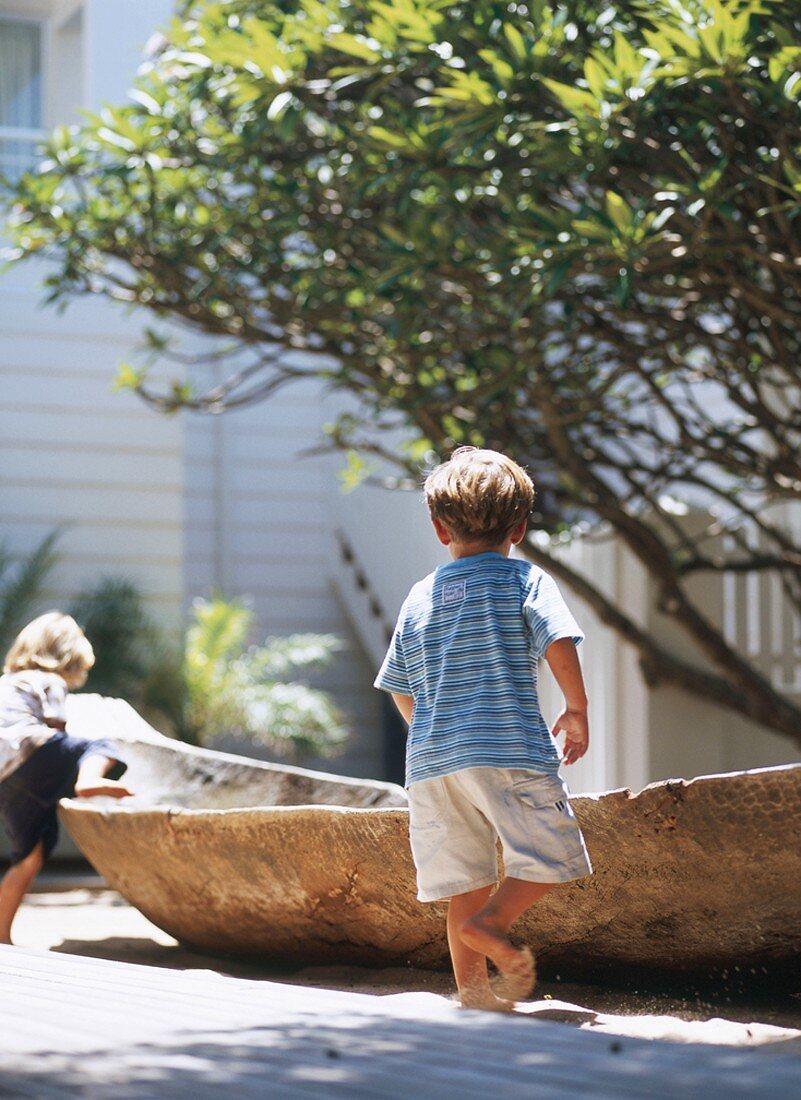 Boys playing in sand around dugout canoe