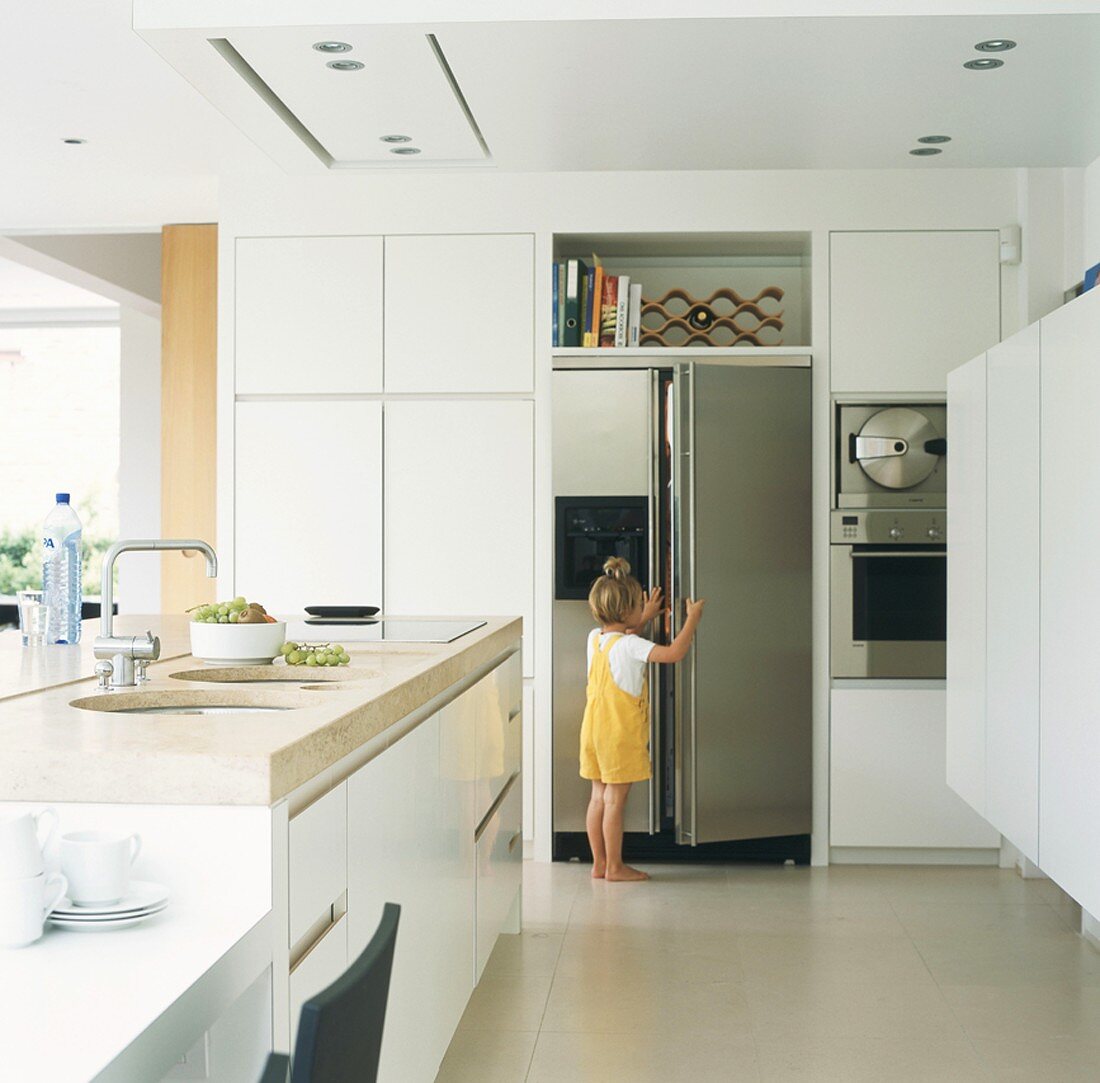 Little girl opening fridge in kitchen