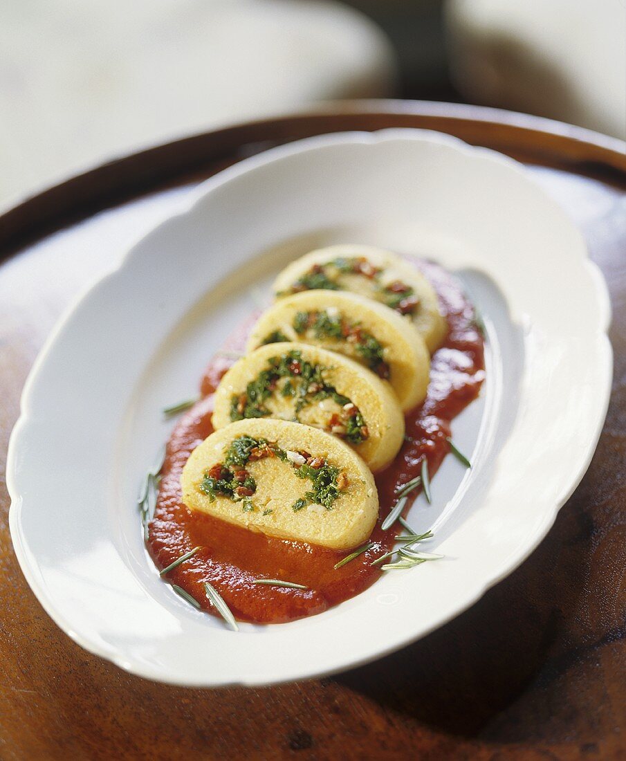 Semolina roulade with kale filling on tomato sauce