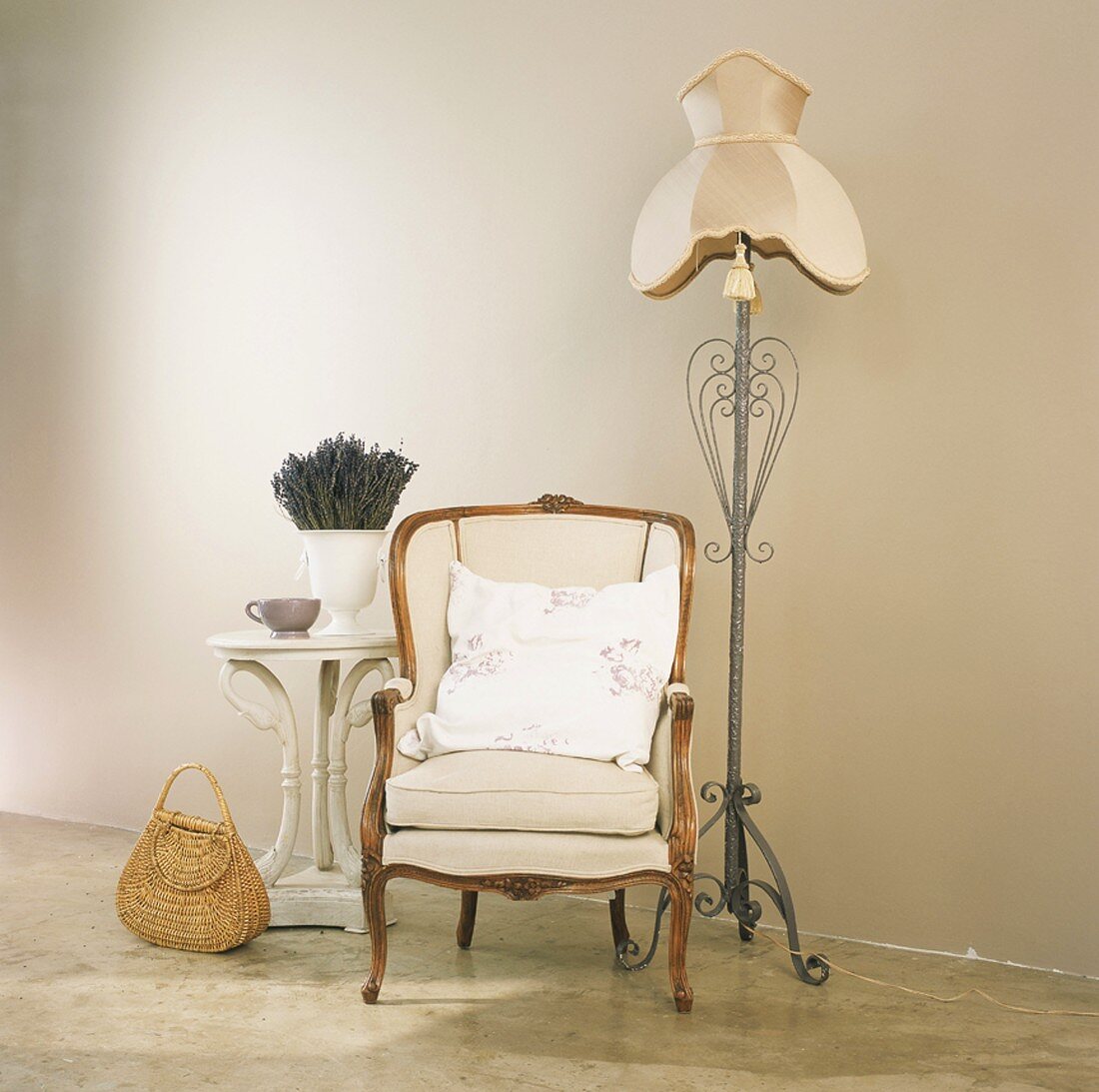 Romantisches Arrangement von Sessel, Stehlampe und Beistelltisch in Cremetönen