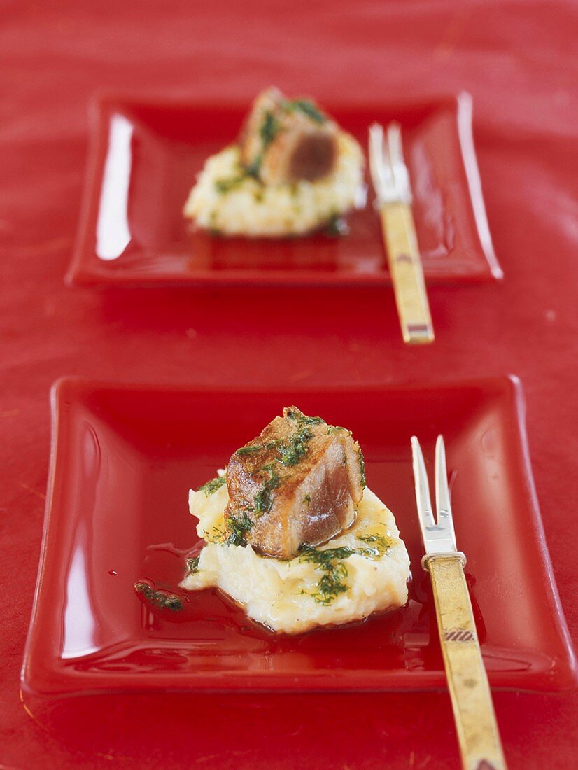 Tuna fish on mashed potatoes in red dishes