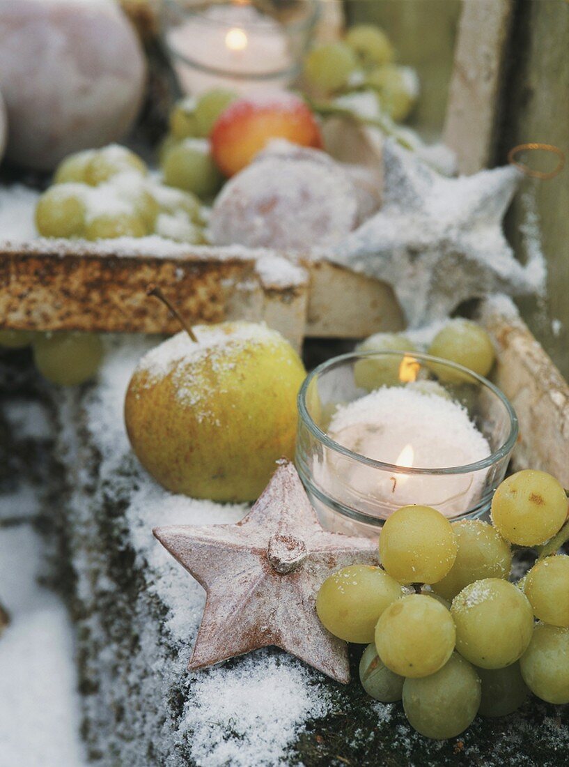 Plastik-Früchte mit Kunstschnee und Windlicht zu Weihnachten