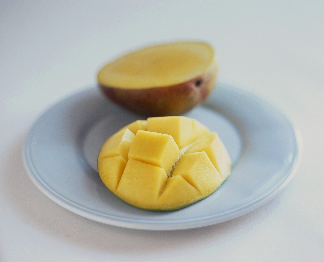 Halbierte und eingeschnittene Mango auf Teller