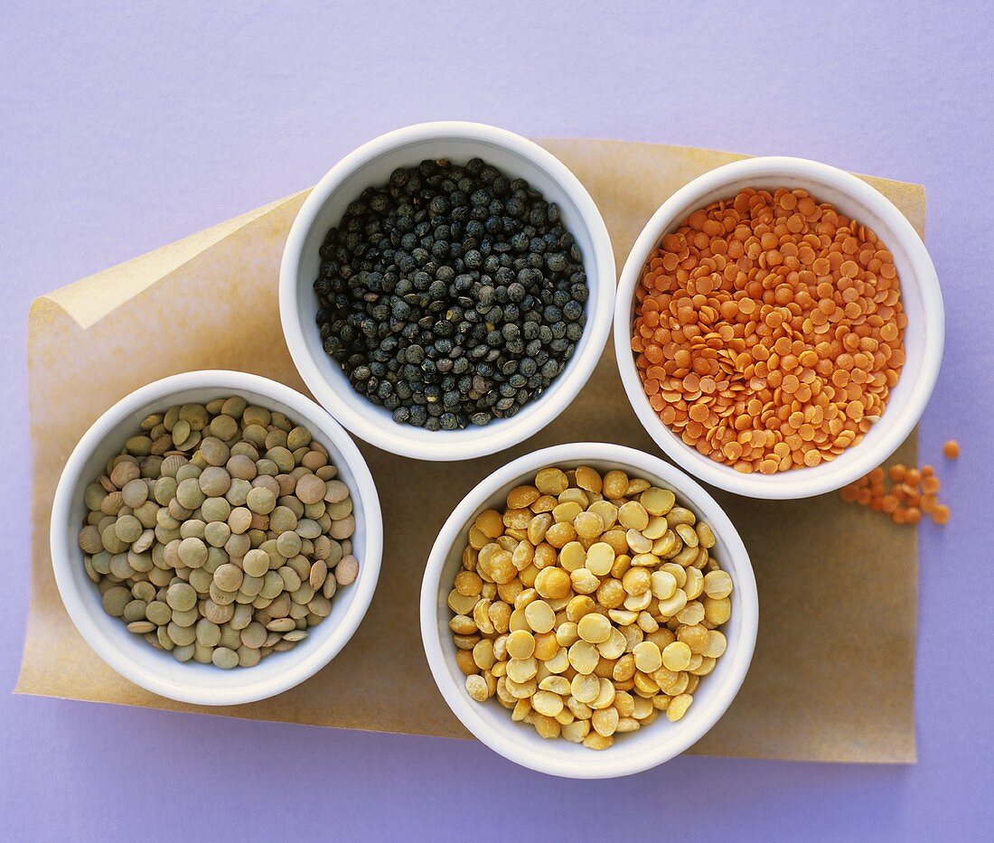 Different types of lentils & split peas in four small bowls