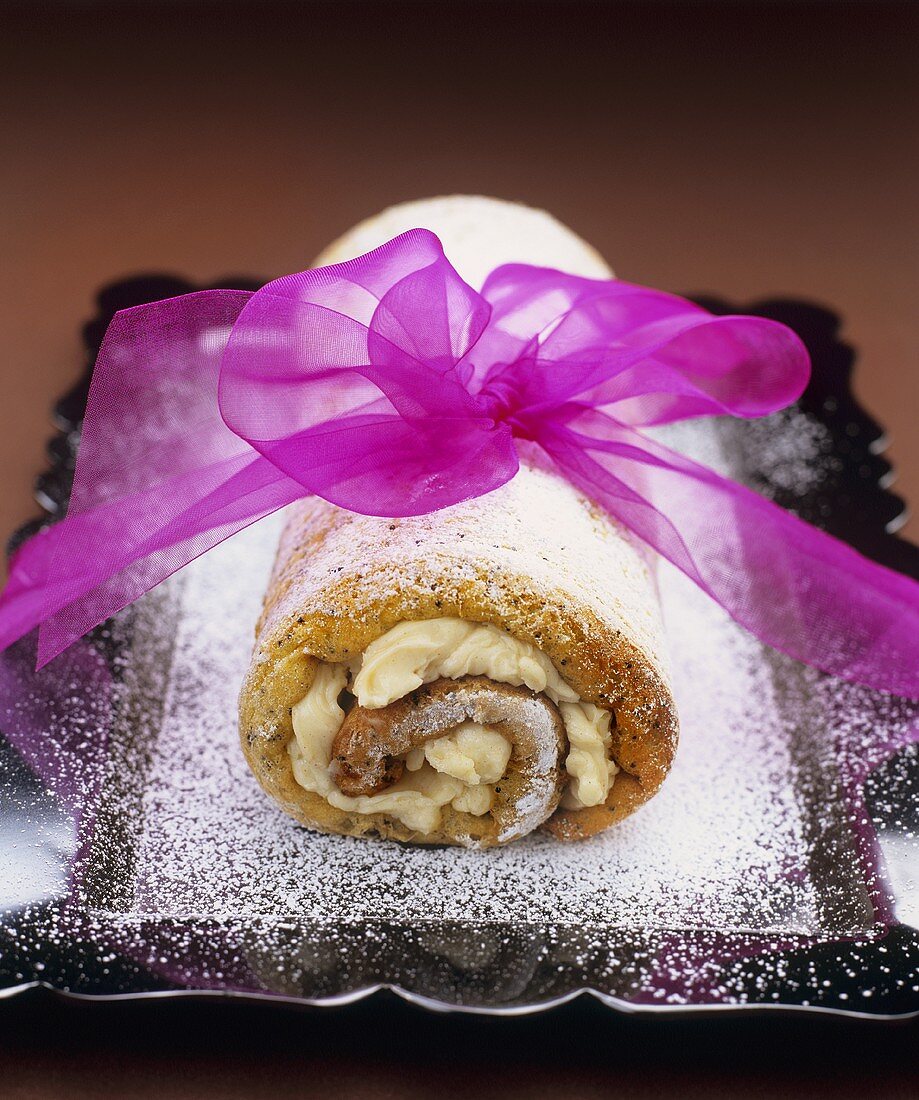Poppy seed and cinnamon sponge roulade with icing sugar and pink bow