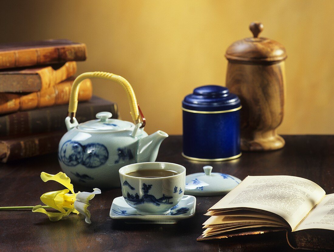 Green tea in cup and pot, books in background and foreground