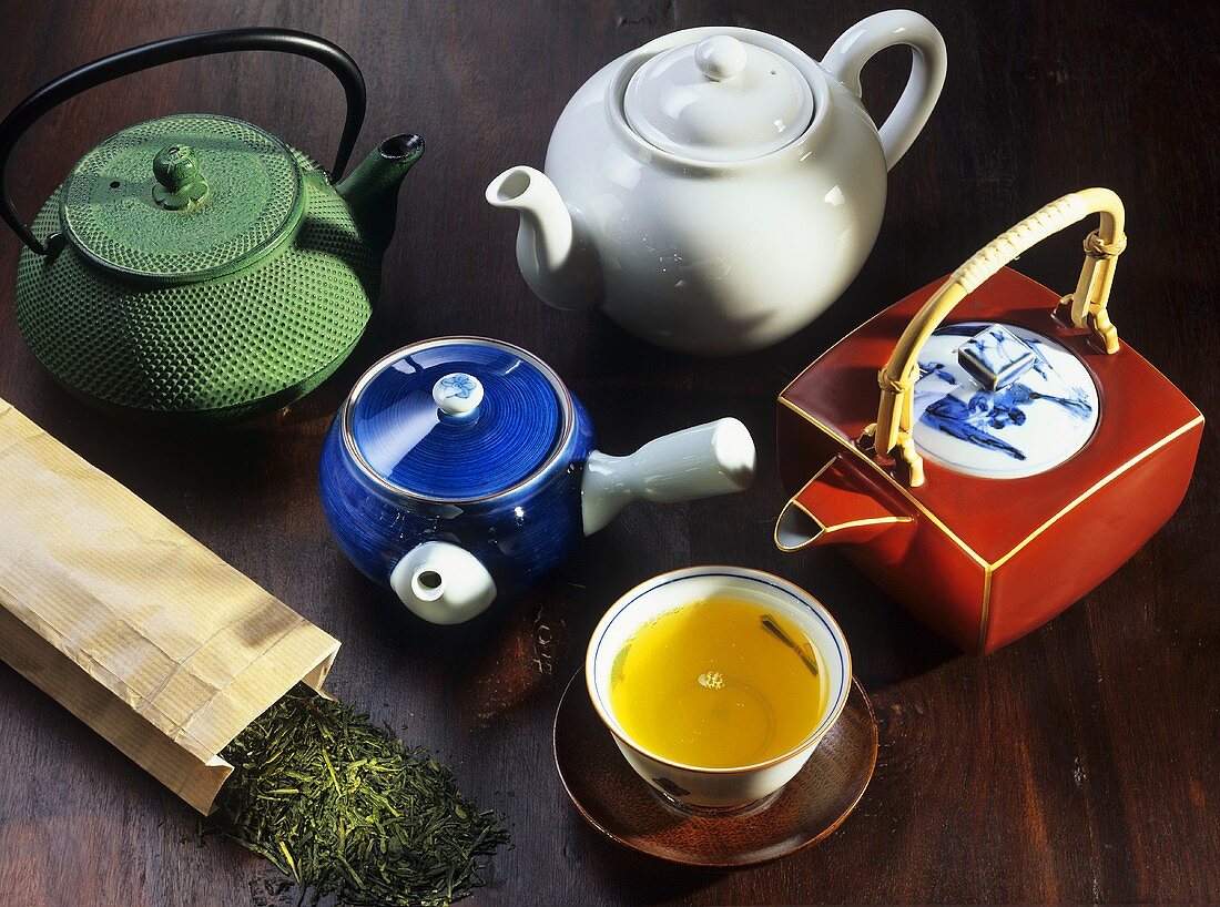 A bowl of green tea and various teapots