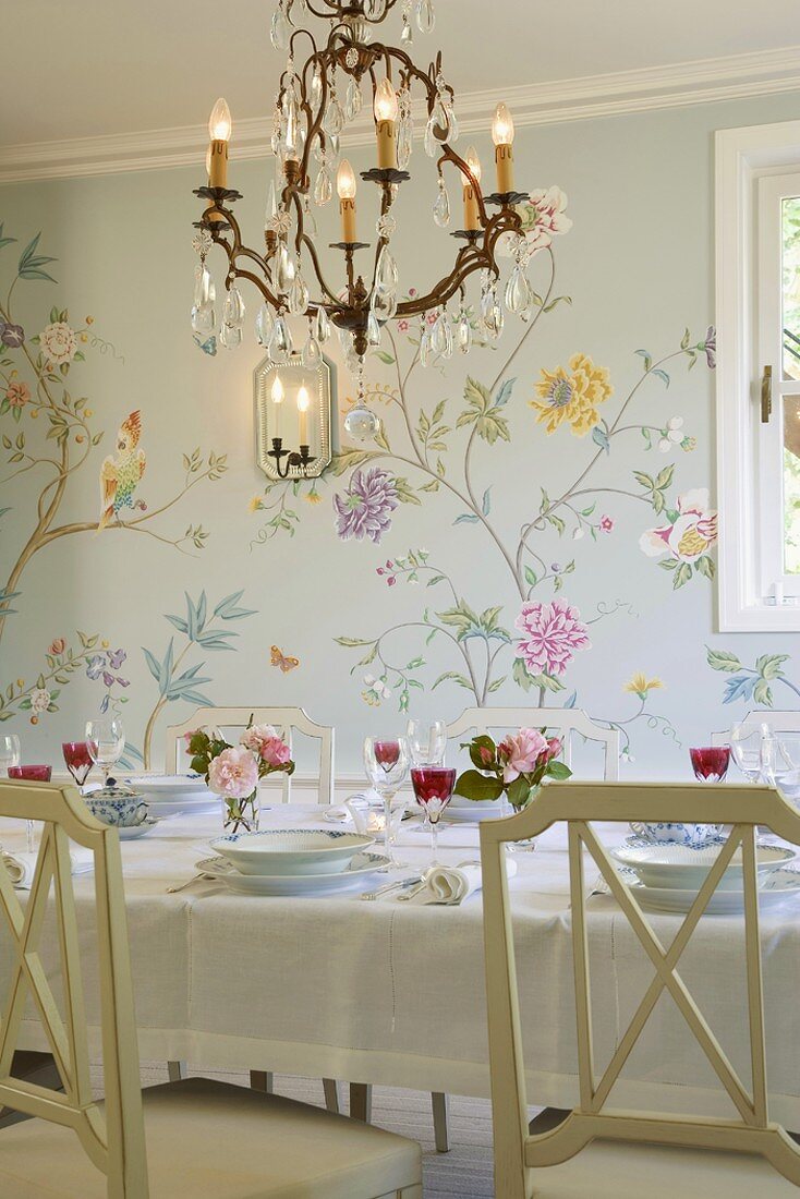 Romantisches Ambiente im Esszimmer mit floraler Wandmalerei und gedecktem Esstisch
