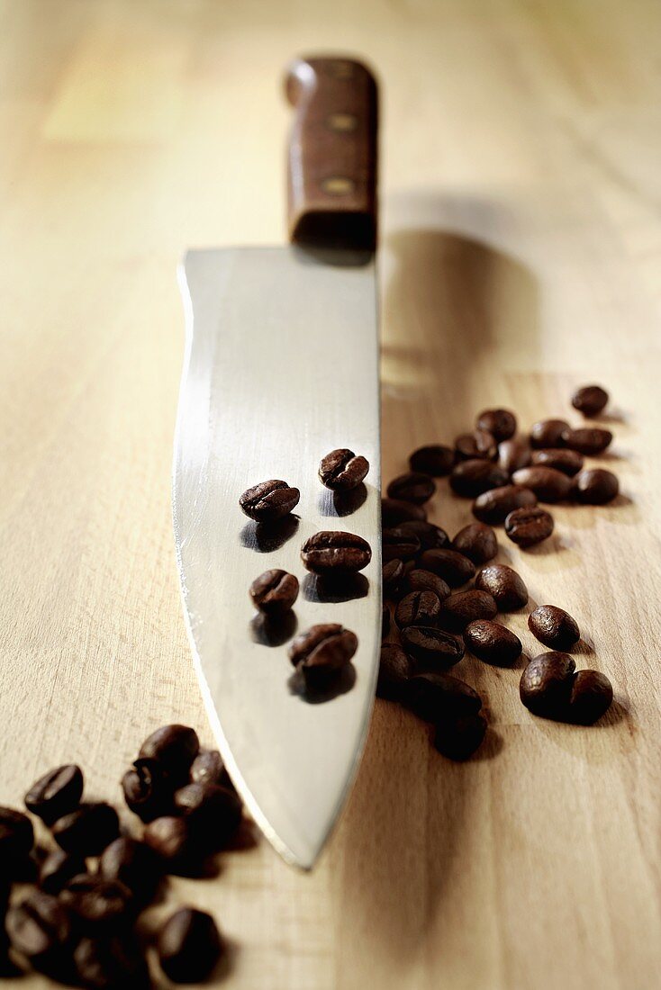 Coffee beans on and beside a knife