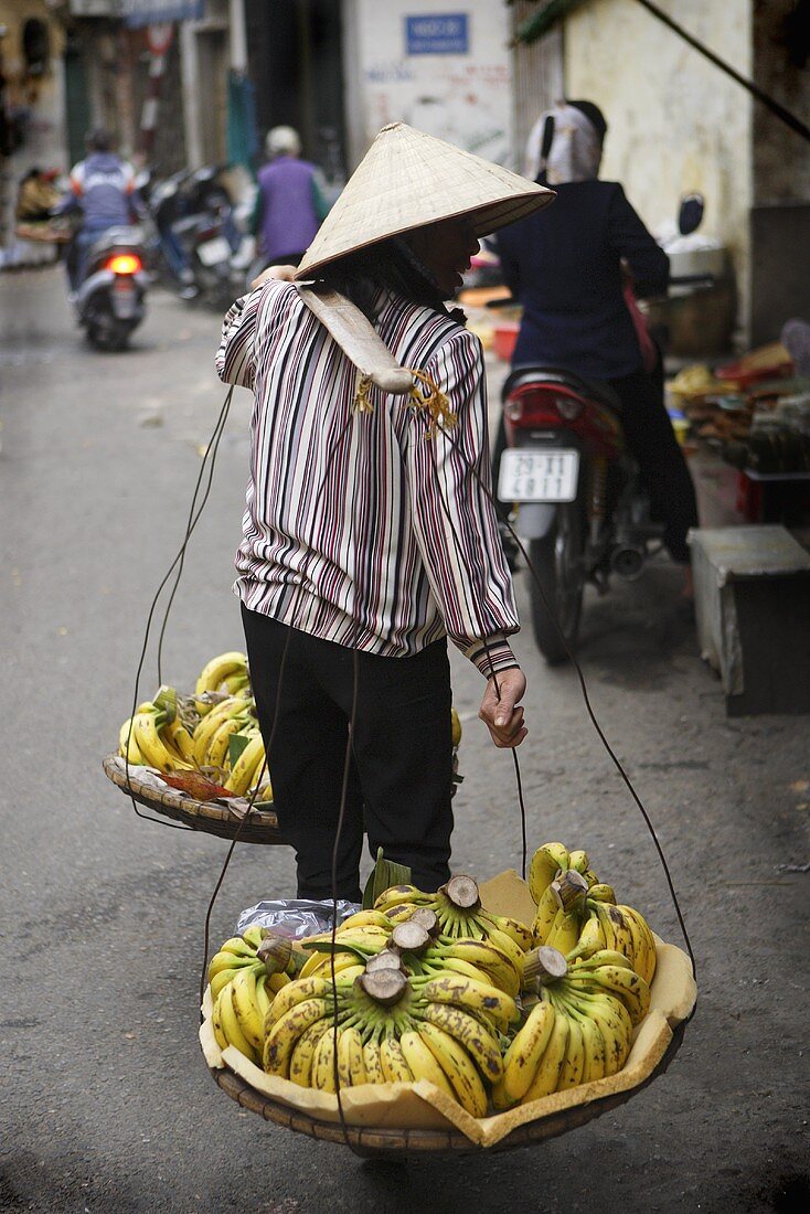 Vietnamese woman carrying bananas in 'don ganh' (carrying yoke)