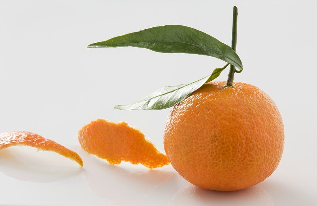 Ungeschälte Clementine und Clementinenschalen